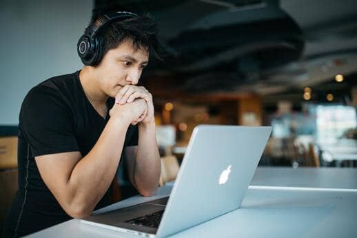 man wearing headphones taking studying on his mac 