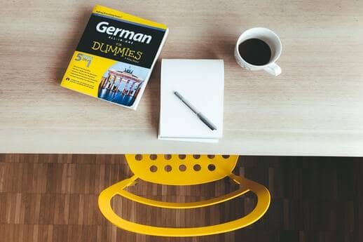 german for dummies book on table next to coffee and pad and pen
