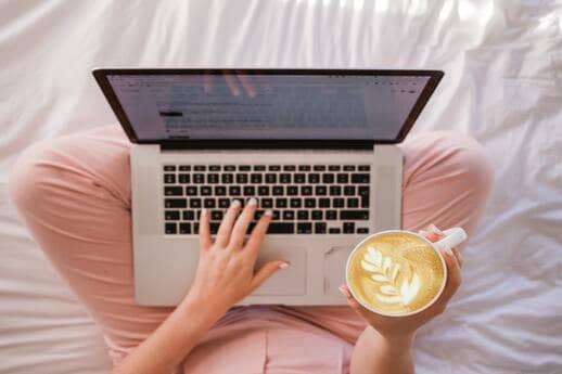 woman blogging while holding a cappuccino